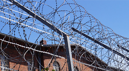 Stacheldraht auf Gef&auml;ngnismauer